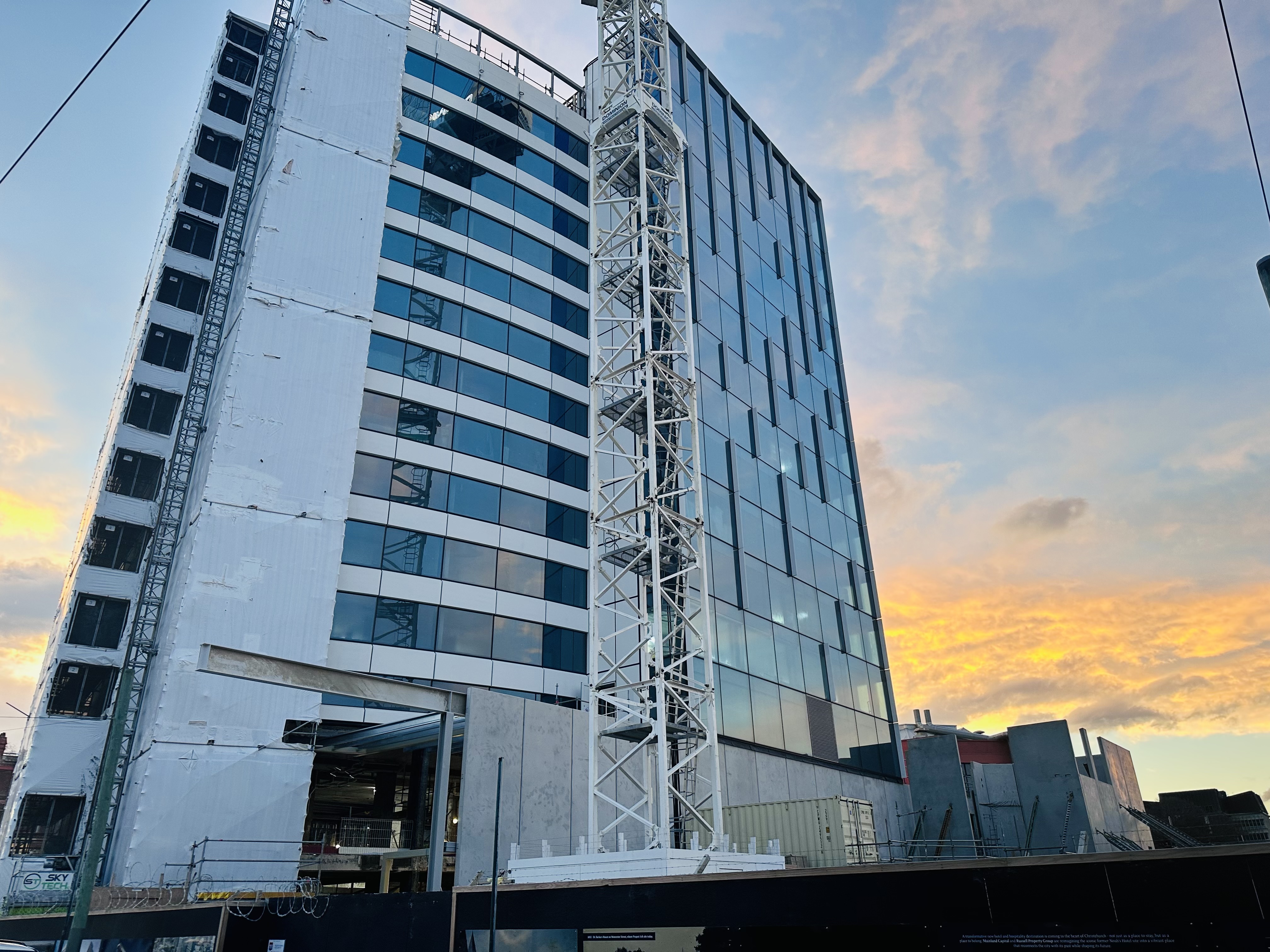 Side view of the Sheraton Christchurch redevelopment with cranes and a colourful evening sky.